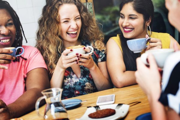Three women laughing in a coffee shop