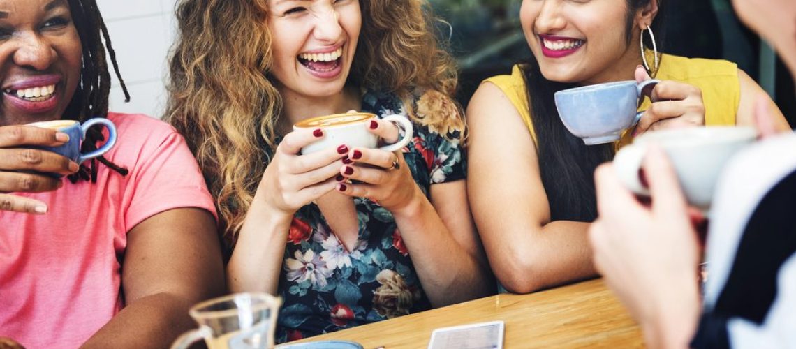 Three women laughing in a coffee shop